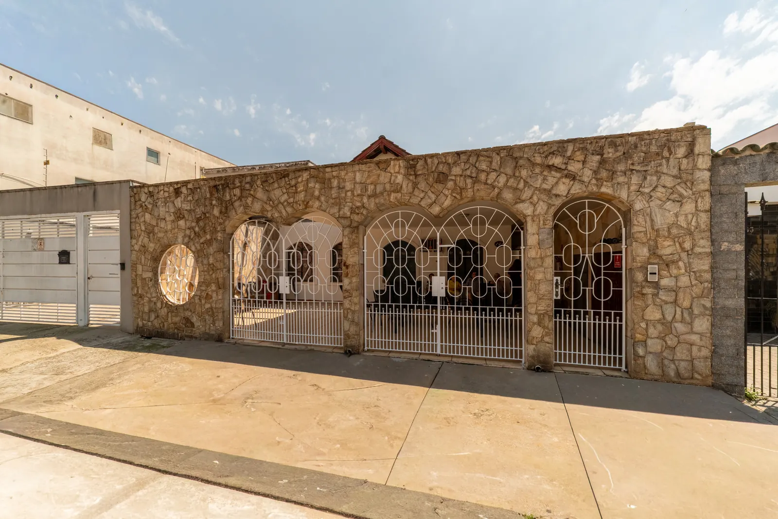 Fachada de pedra do Residencial Laços de Vida com três portões brancos em arco